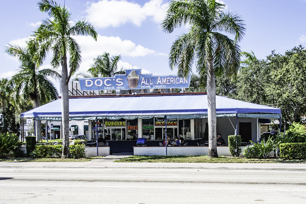 Retro diner with palm trees and awning.